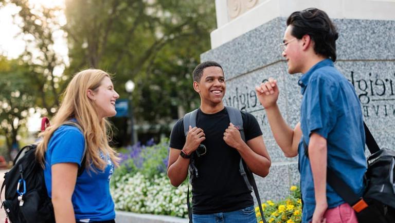 Students standing by Creighton pillar on the mall