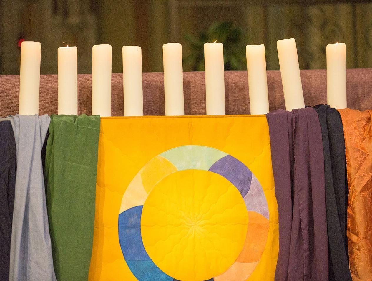 An altar decorated for the Interfaith Prayer Service with candles and an Interfaith banner