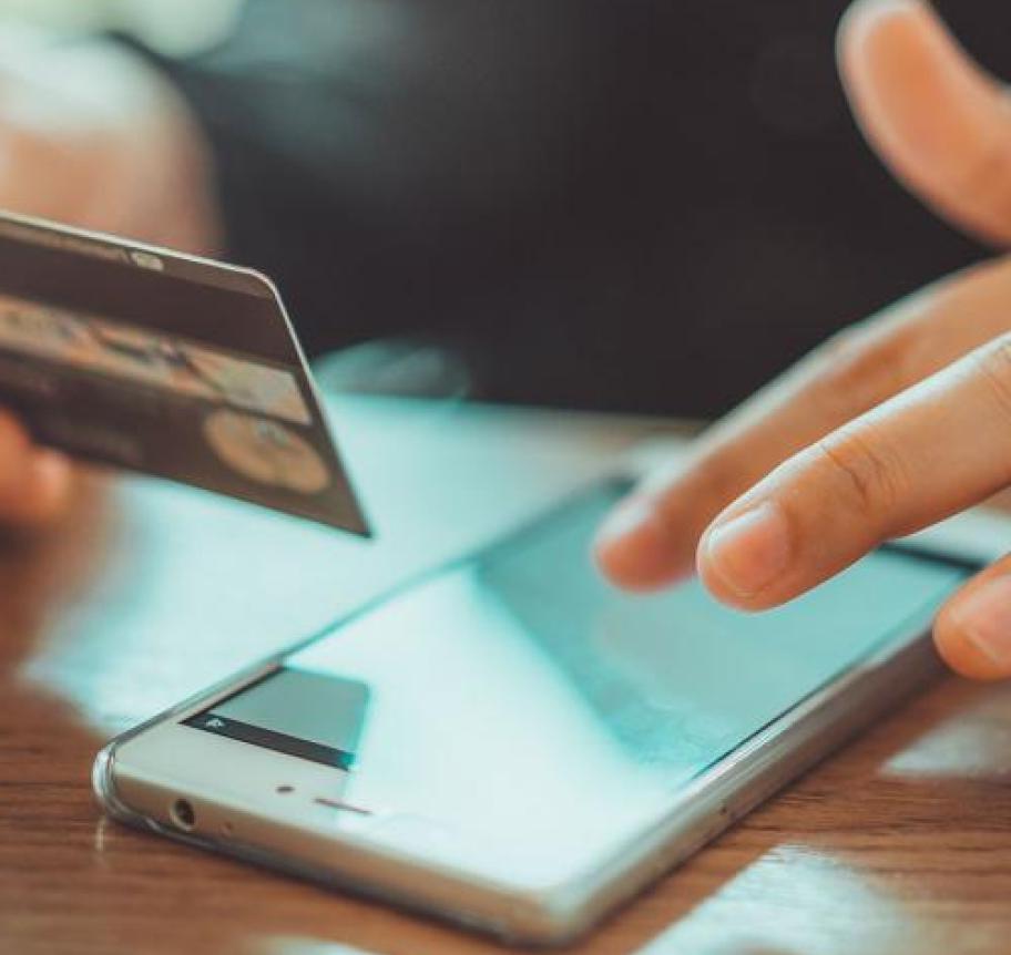 Closeup of a person holding a credit card while using a mobile device