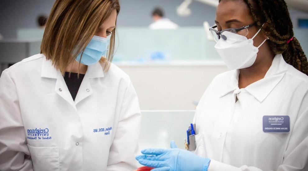 Dean Wallen in lab setting with another woman wearing masks and gloves.